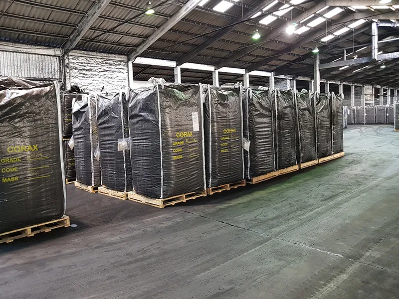 Rows of large black bulk bags on pallets in a warehouse