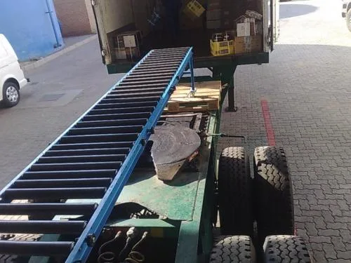 A roller conveyor running into the back of a truck at a loading bay